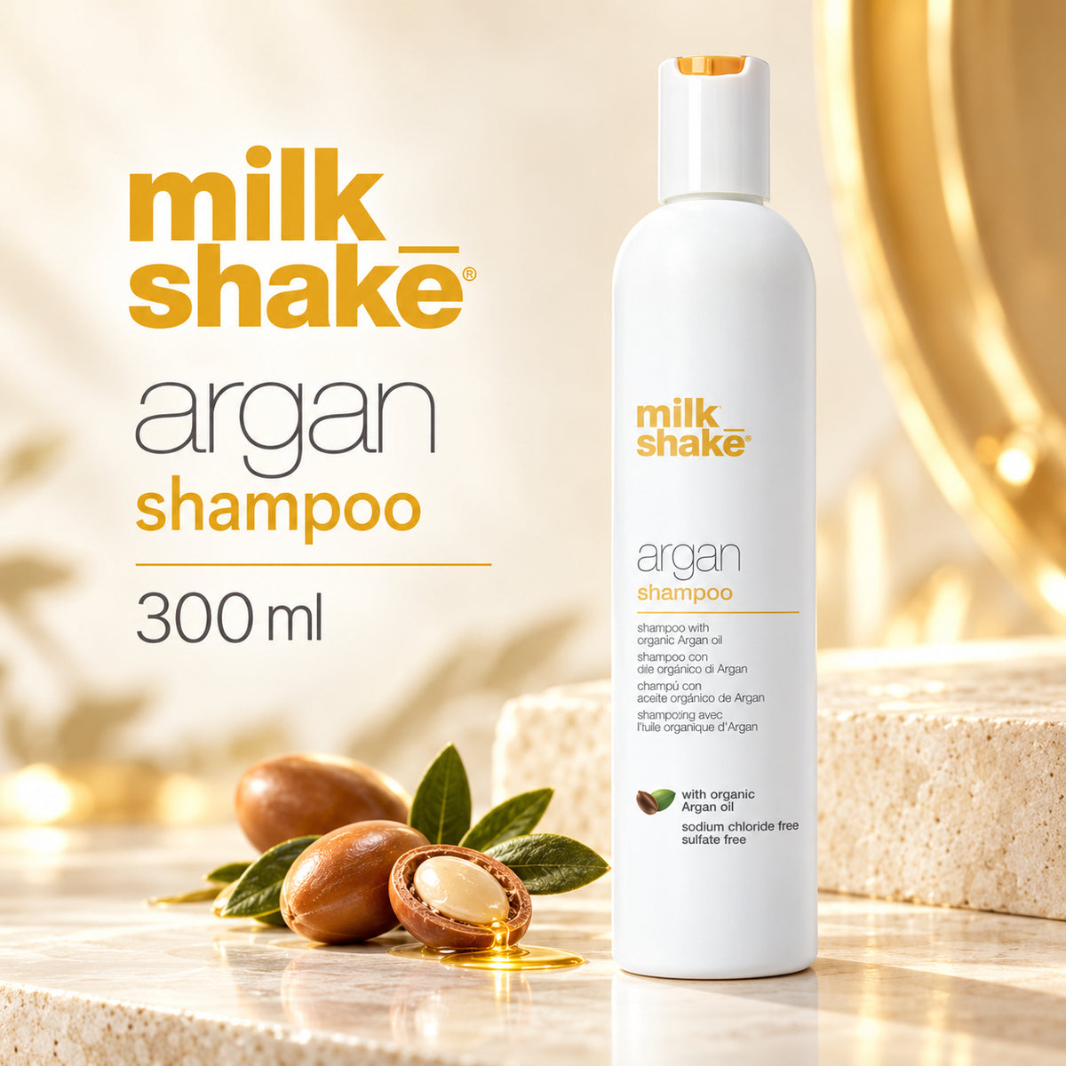 A 300 ml bottle of milk shake argan shampoo stands on a marble surface with argan nuts and leaves in the foreground, against a warm, softly lit background with gold-toned lighting and text on the left.