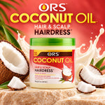 A jar of ORS Coconut Oil Hair & Scalp Hairdress shown on a styled set with coconuts, cream splashes, and a red background. The product container has a green lid and a red and white label with coconut imagery.