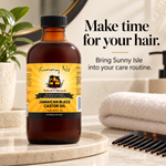 A bottle of Sunny Isle Jamaican Black Castor Oil stands on a marble tray in a bathroom setting, with a folded towel, hair comb, and decorative plant in the background. Text on the image reads, 'Make time for your hair.