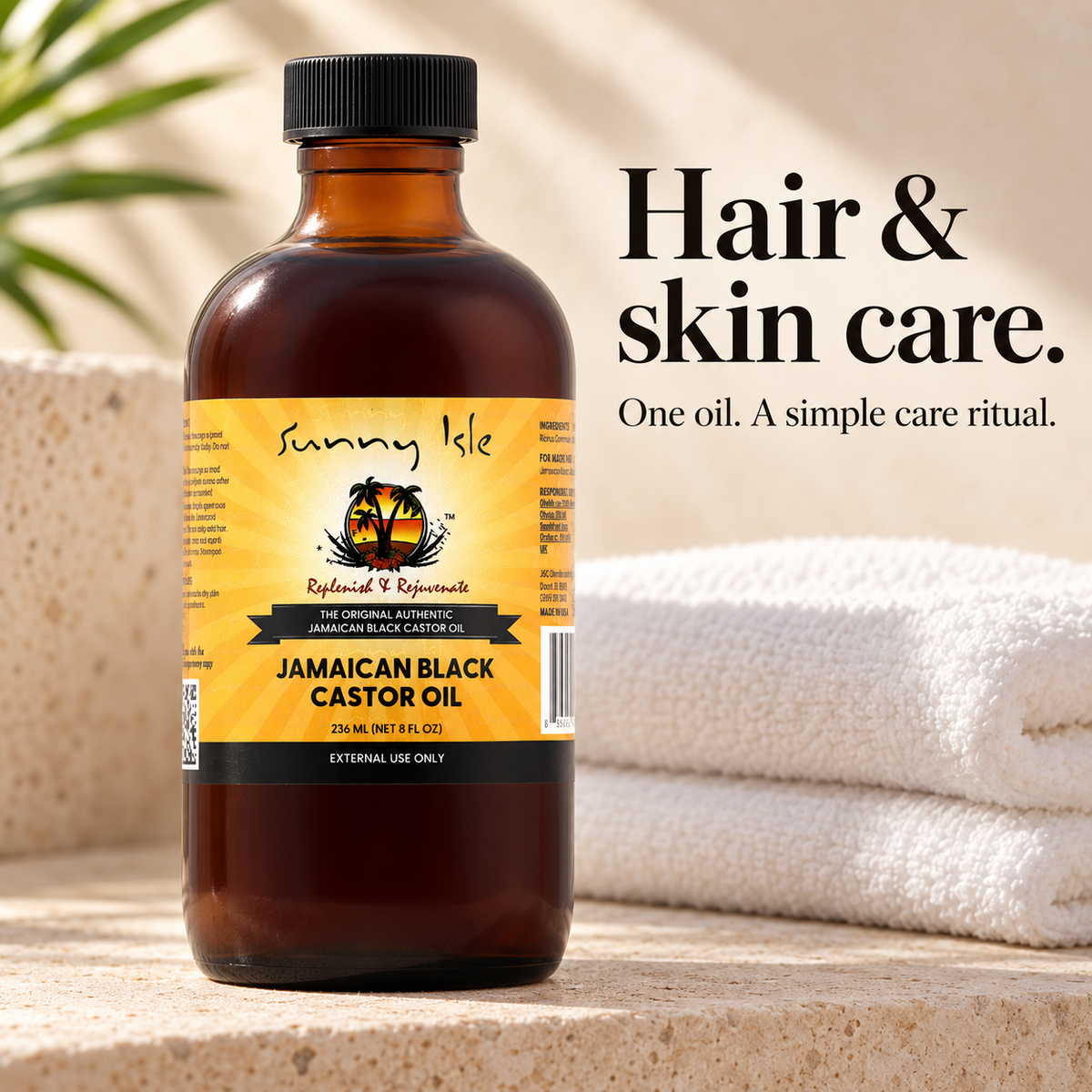 A bottle of Sunny Isle Jamaican Black Castor Oil stands on a stone surface with folded white towels and a blurred plant in the background. Text on the right reads 'Hair & skin care.